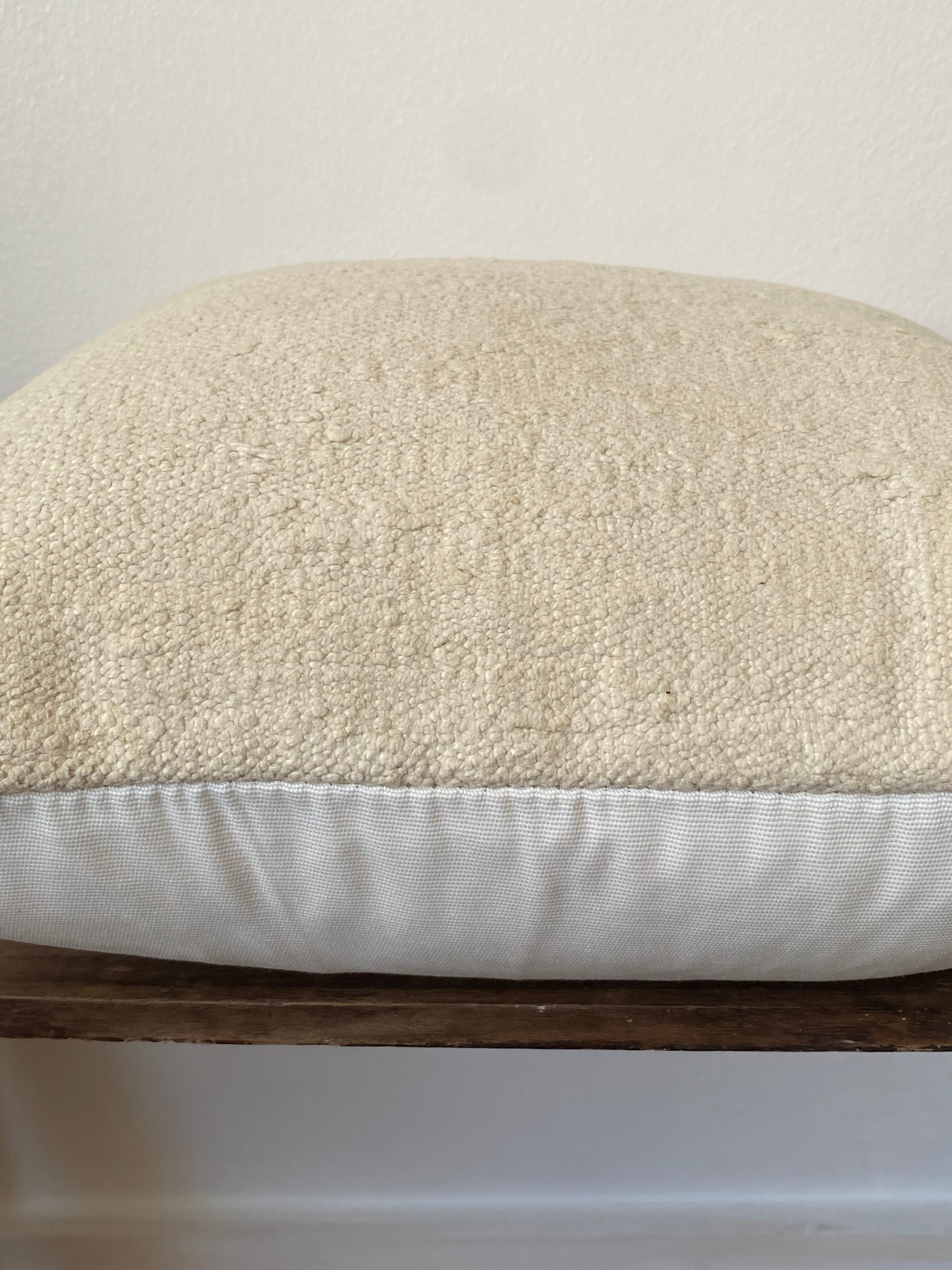 Close-up of a textured off white Kilim pillow cover  on wooden shelf