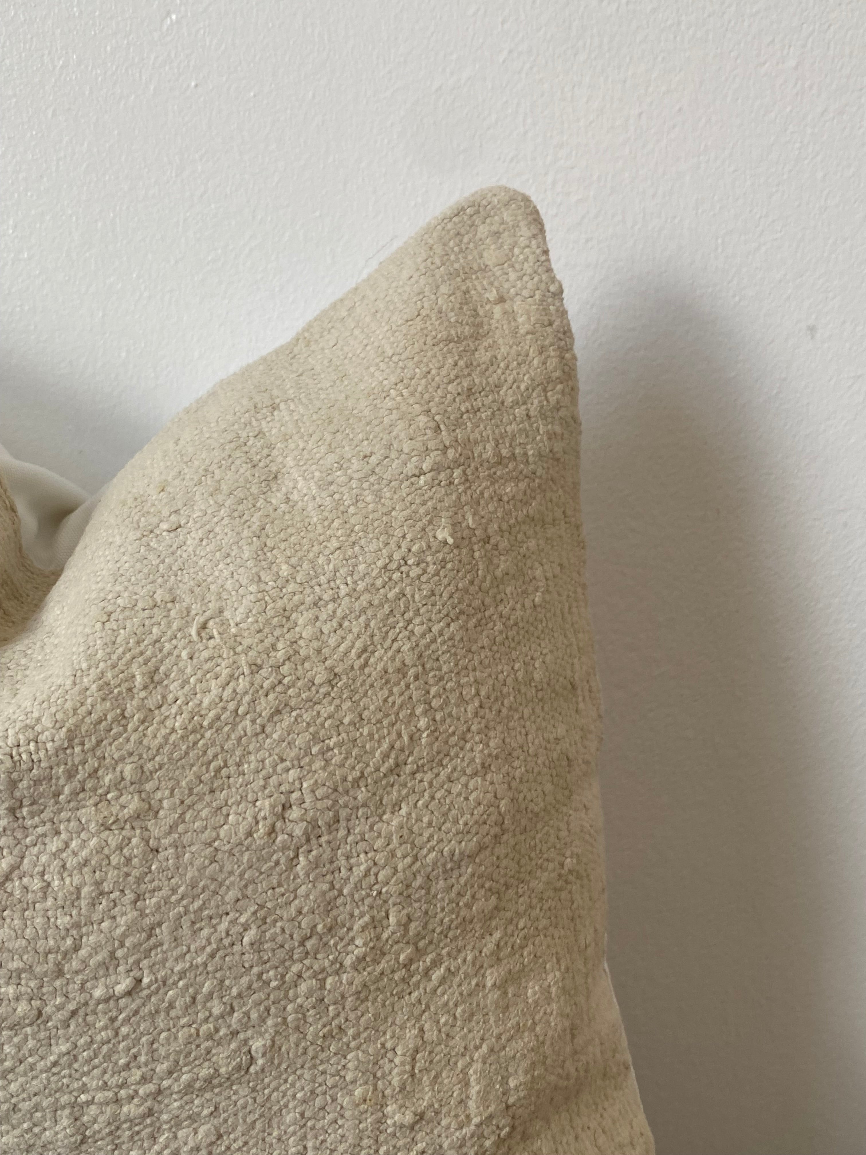 Textured off white pillow cover on a wooden table