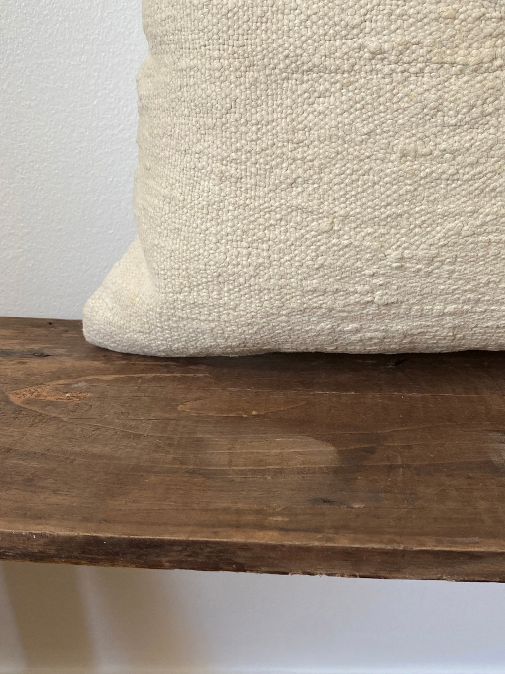 Textured off white pillow cover on a wooden surface with a neutral background
