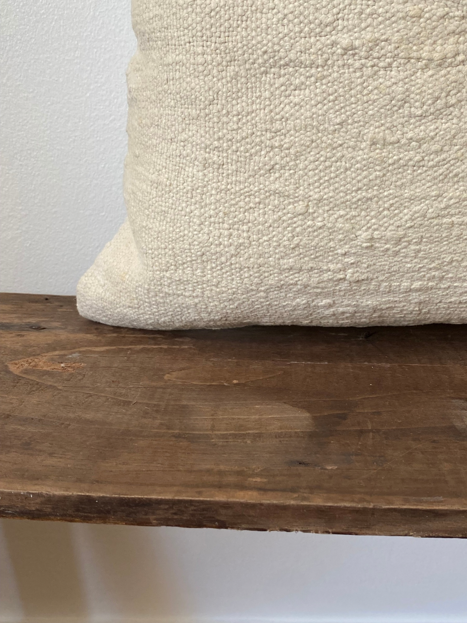 Textured off white pillow cover on a wooden surface with a neutral background