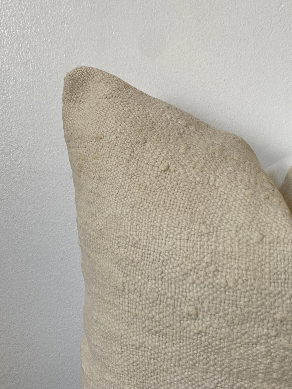 Textured off white pillow cover on a light wooden background