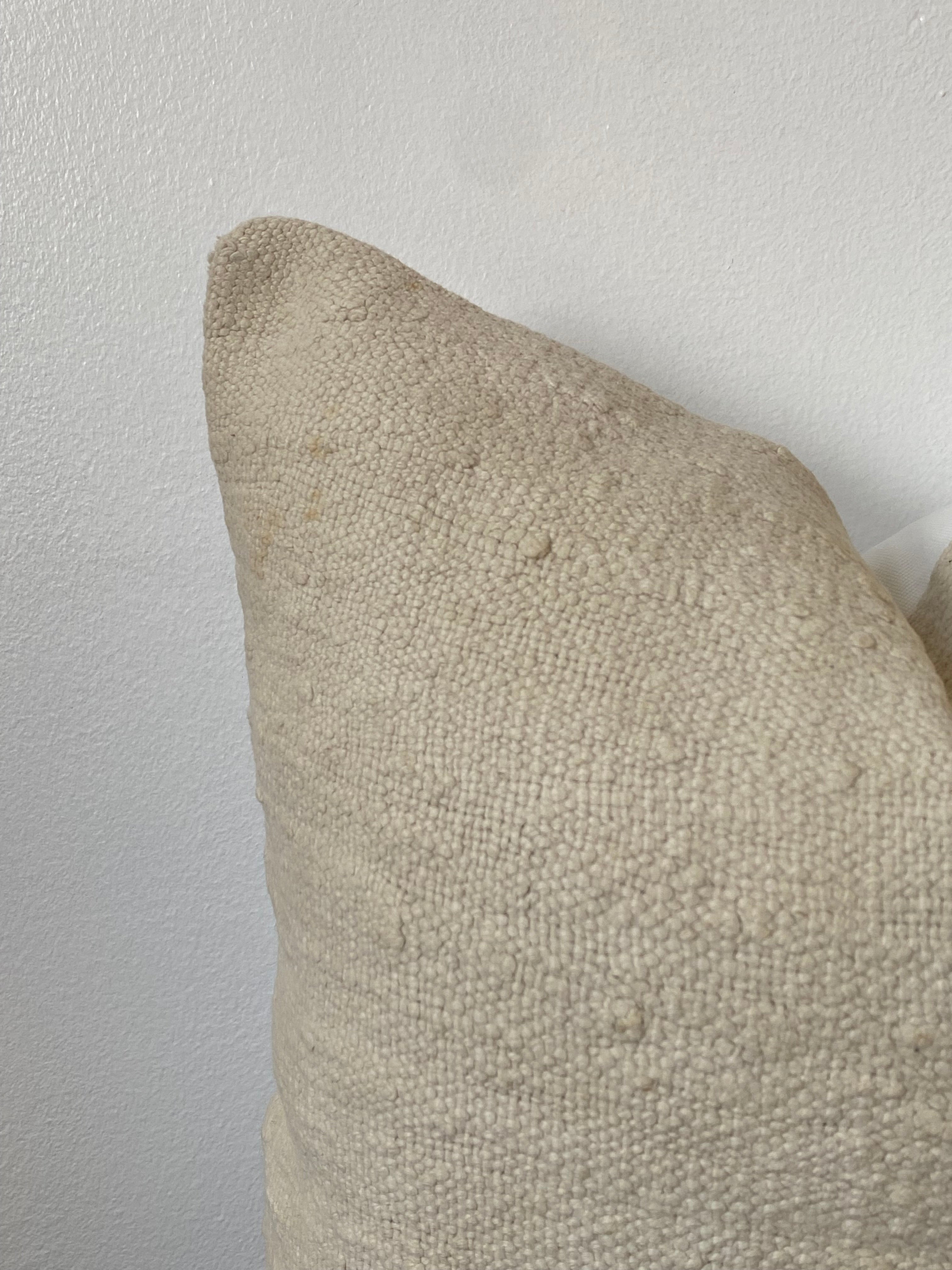 Textured off white pillow cover on a light wooden background