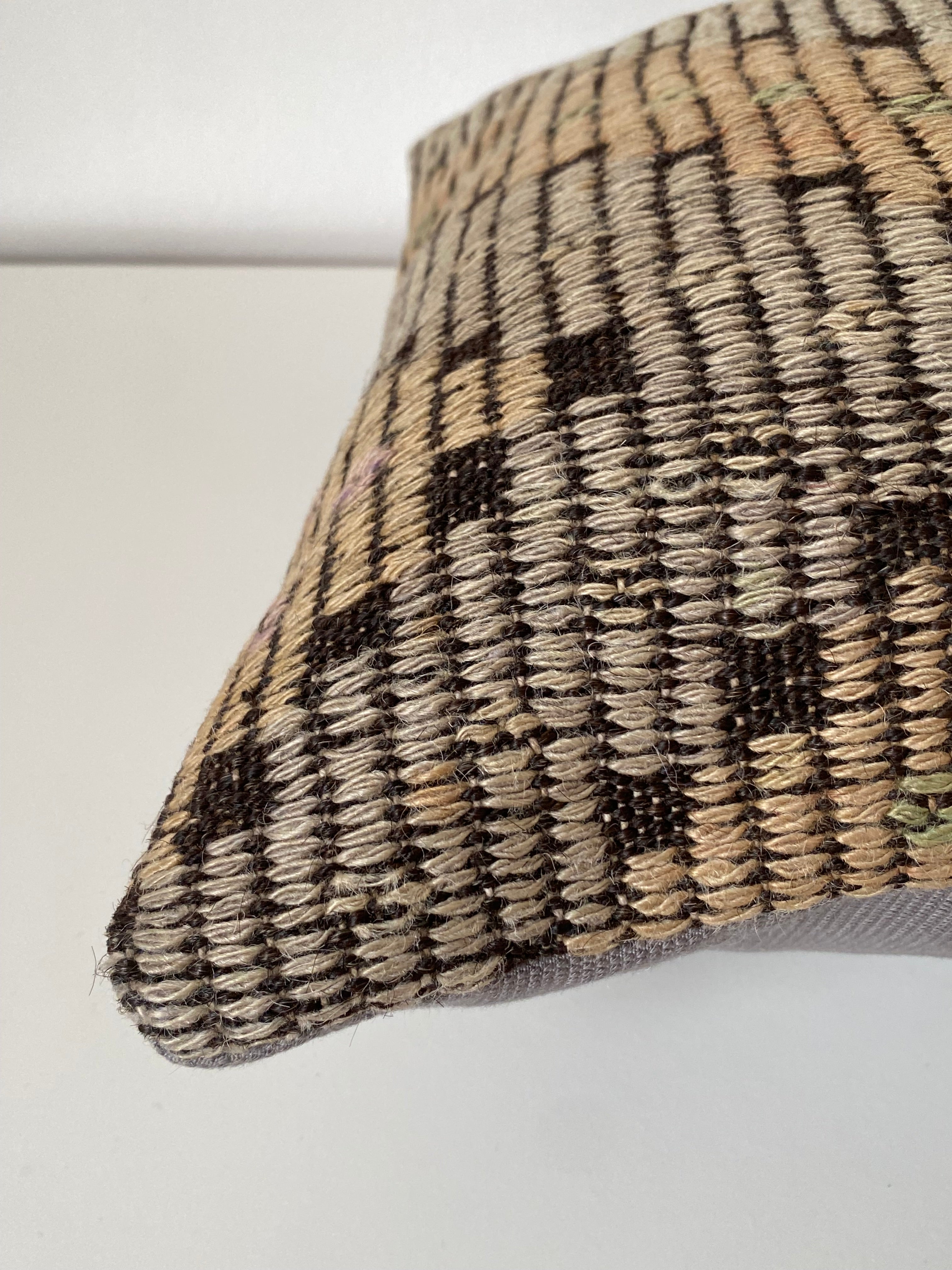 Textured Turkish kilim pillow cover with geometric pattern on a light grey background