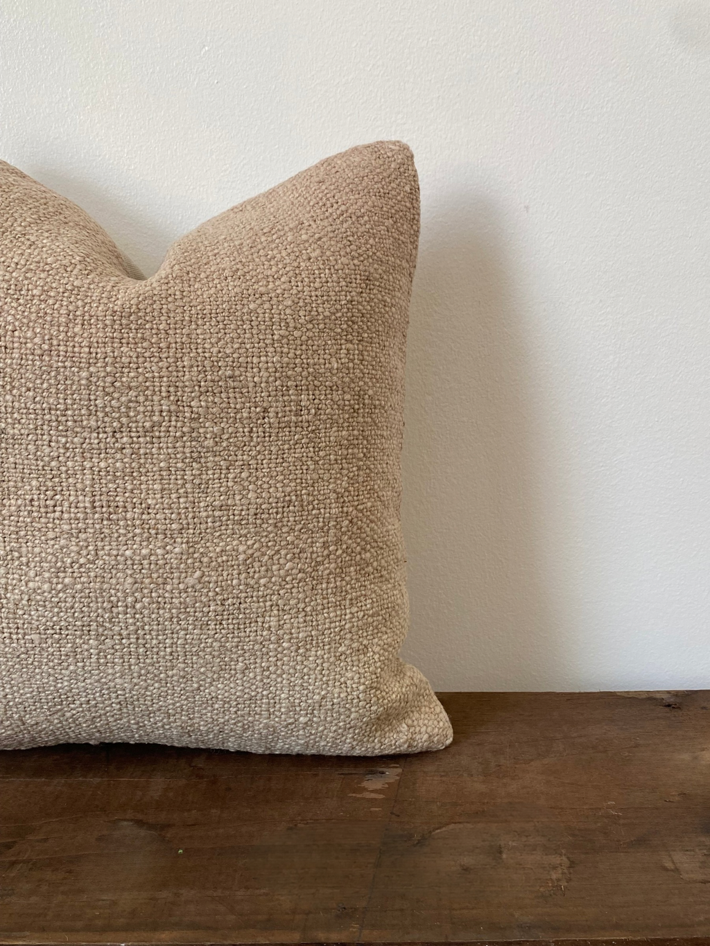 Textured beige Turkish Kilim pillow cover on a wooden surface with a white background