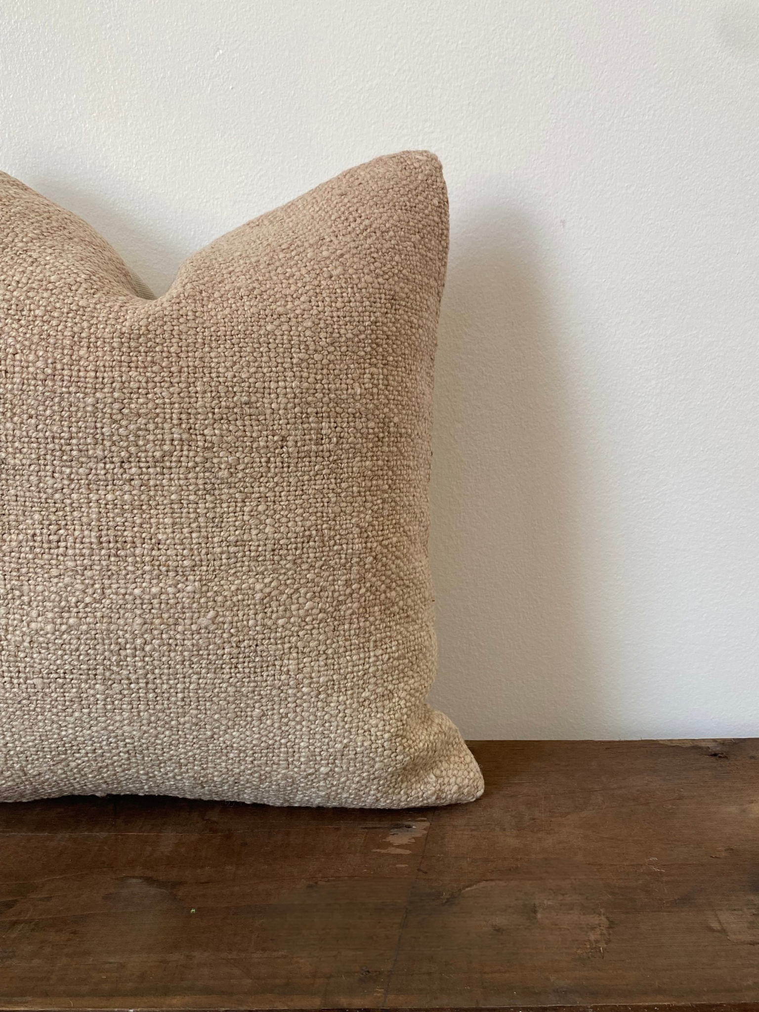 Textured beige Turkish Kilim pillow cover on a wooden surface with a white background