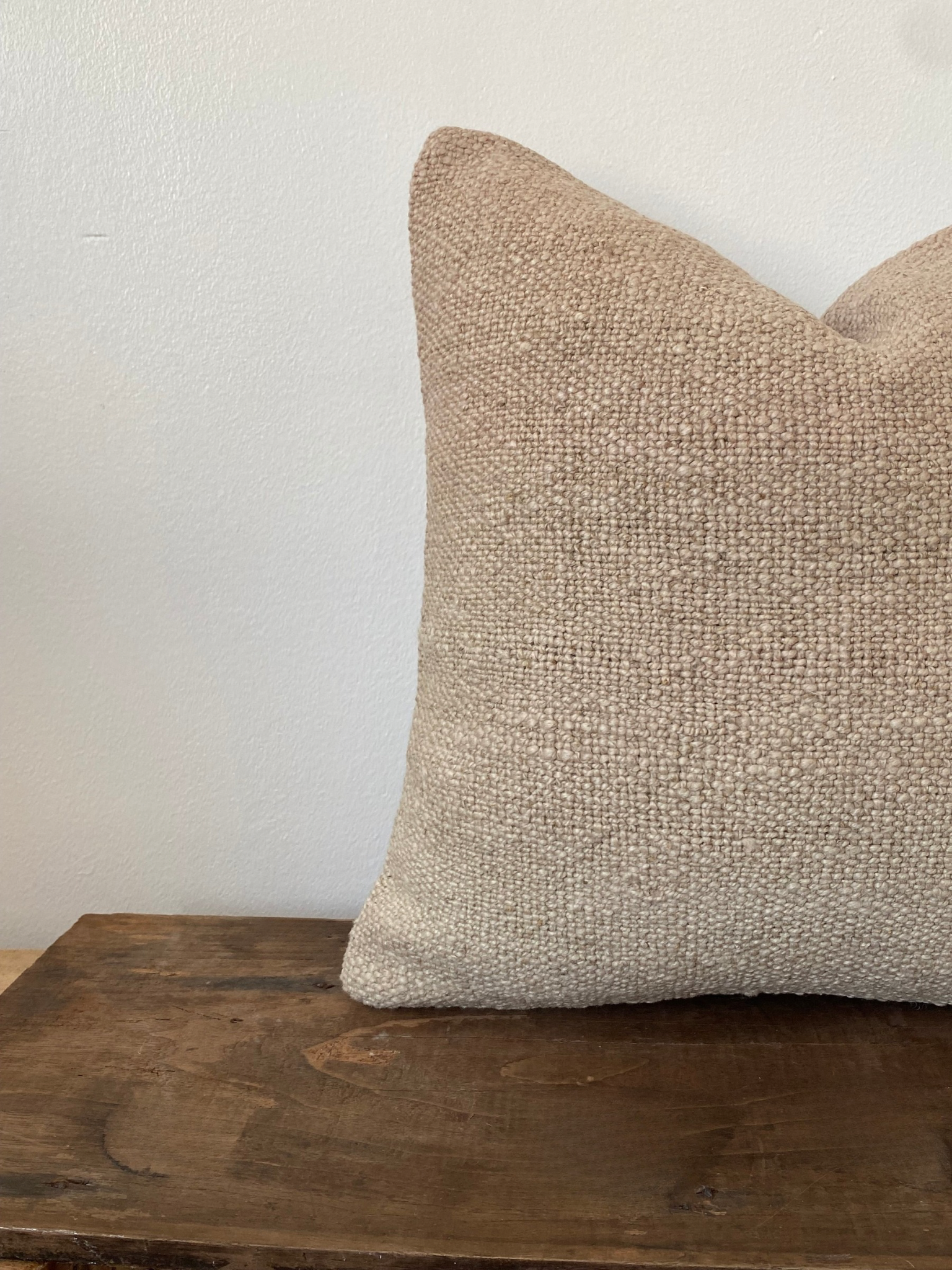 Textured beige Turkish Kilim pillow cover on a wooden surface 
