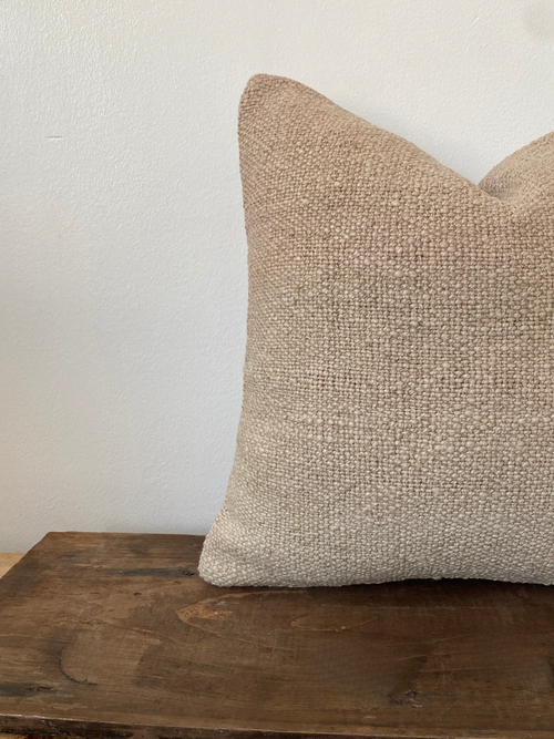 Textured beige Turkish Kilim pillow cover on a wooden surface 