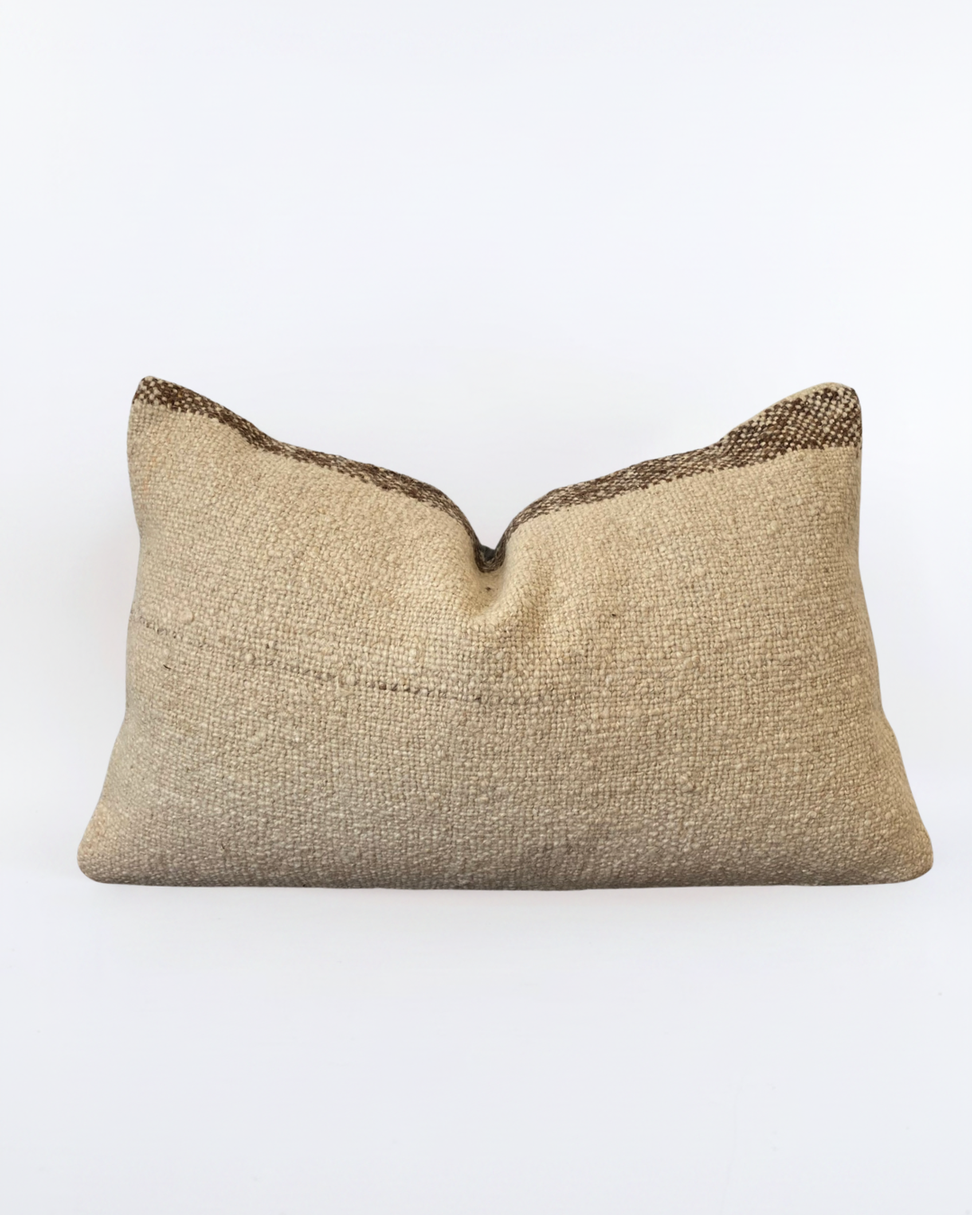 A rectangular Turkish lumbar pillow cover made of natural beige burlap fabric with a decorative dark brown woven trim along the top edge, shown against a plain white background.