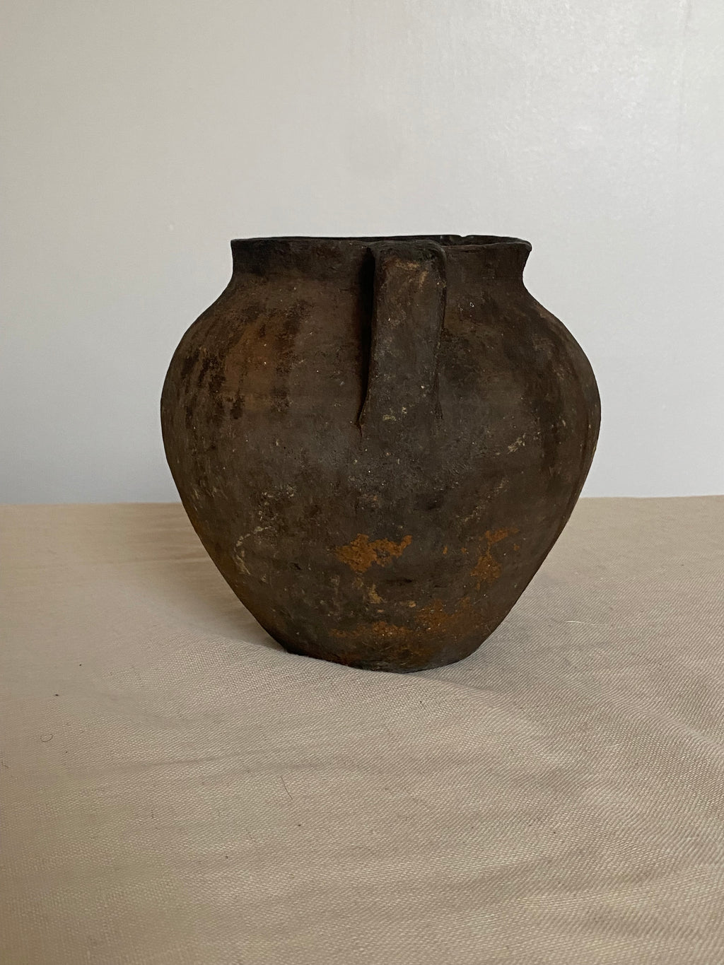 Black and brown antique clay pot on a neutral background 
