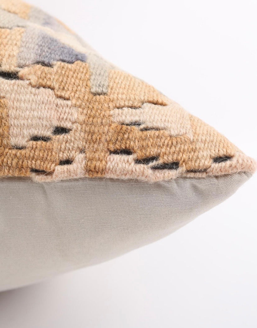 A close up of a Turkish Kilim Pillow cover with geometric coral and beige pattern on a white surface 